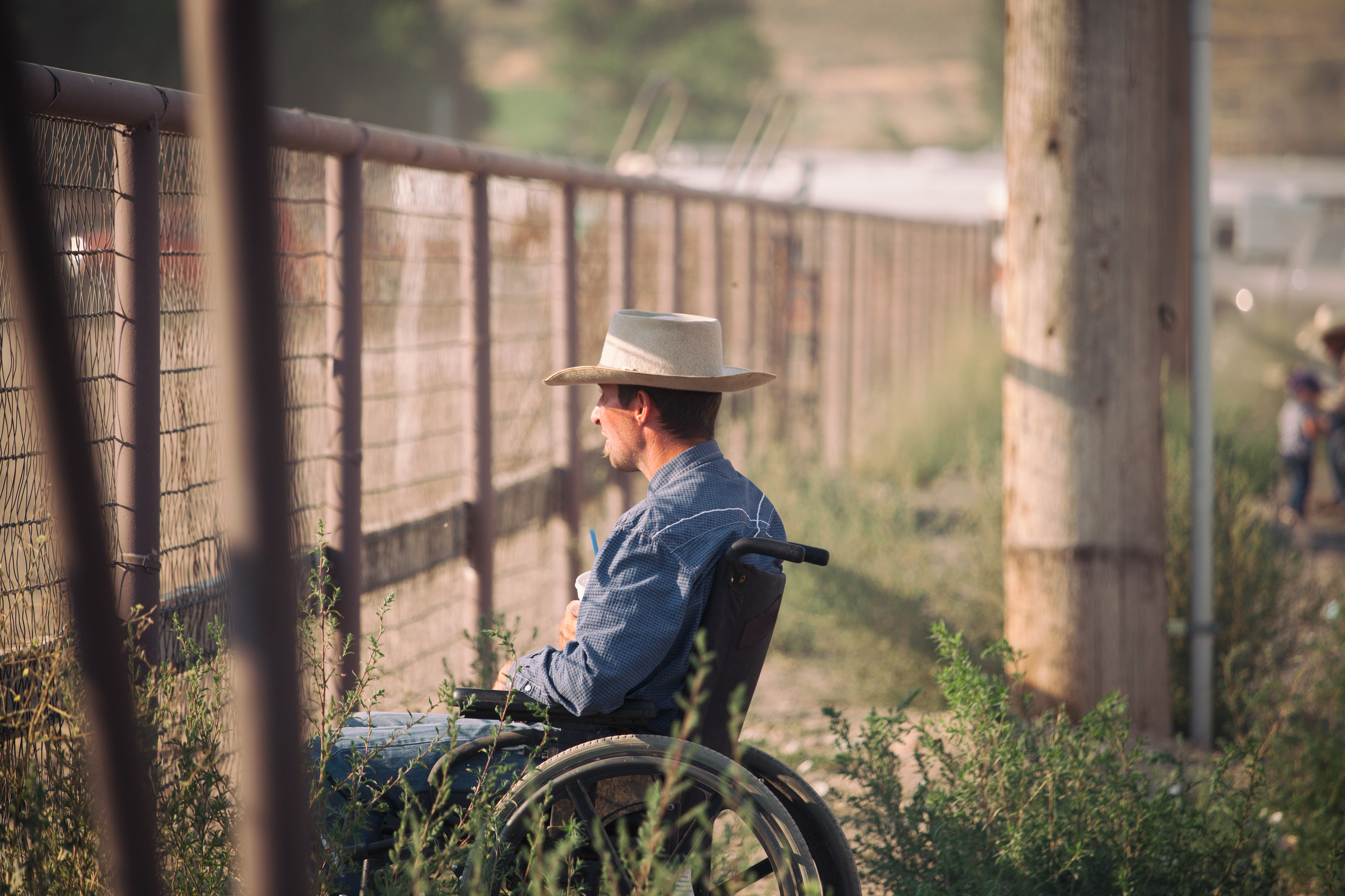 Man in wheelchair in rural area looking out at farm