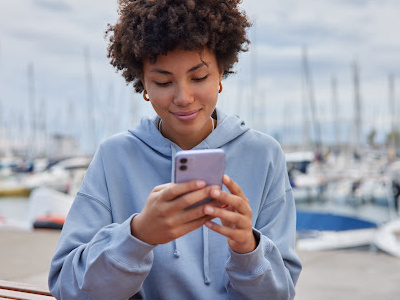 Woman checking phone at marina